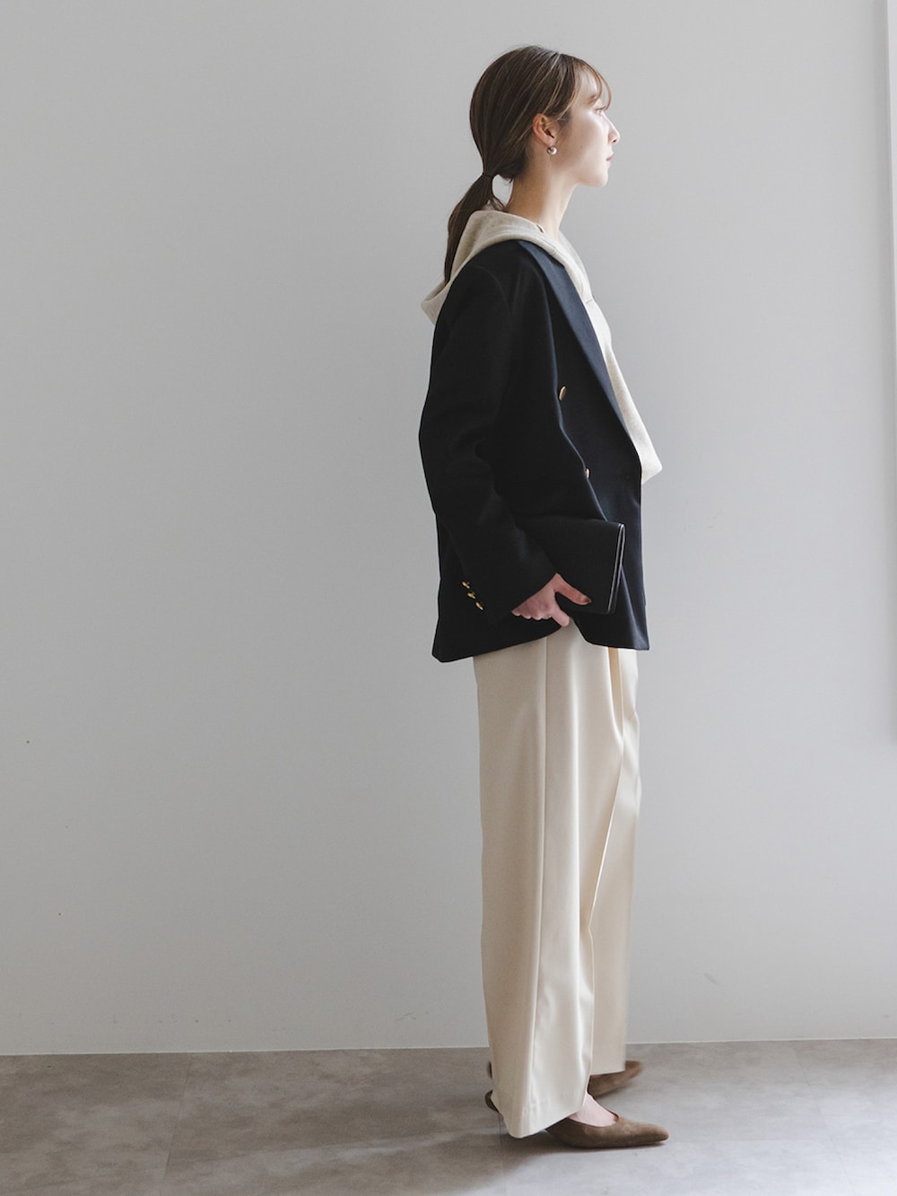 ブラック系のテーラードジャケット、ホワイト系のニット/セーター、ベージュ系のスラックスを着用したレディースの冬コーディネートの2枚目の写真