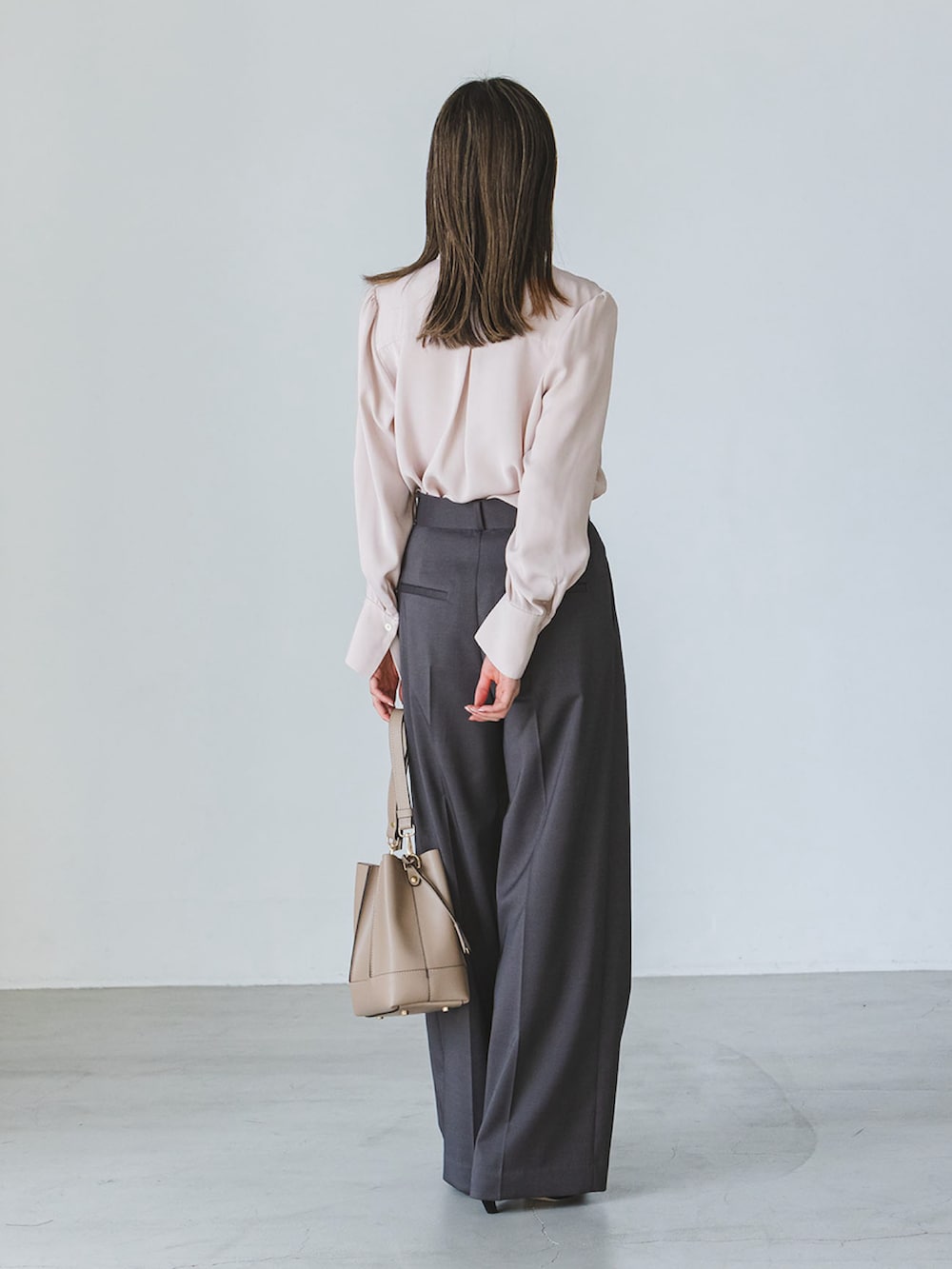 ピンク系のシャツ/ブラウス、グレー系のスラックス、ベージュ系のショルダーバッグを着用したレディースの秋コーディネートの2枚目の写真