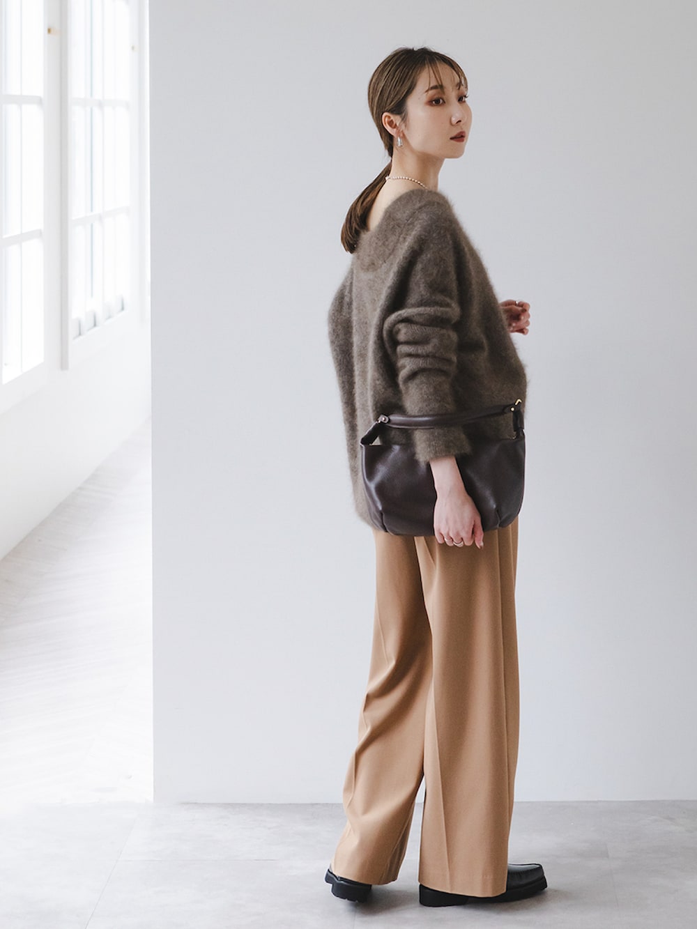 ブラウン系のニット/セーター、イエロー系のスラックス、ブラウン系のショルダーバッグを着用したレディースの秋コーディネートの2枚目の写真