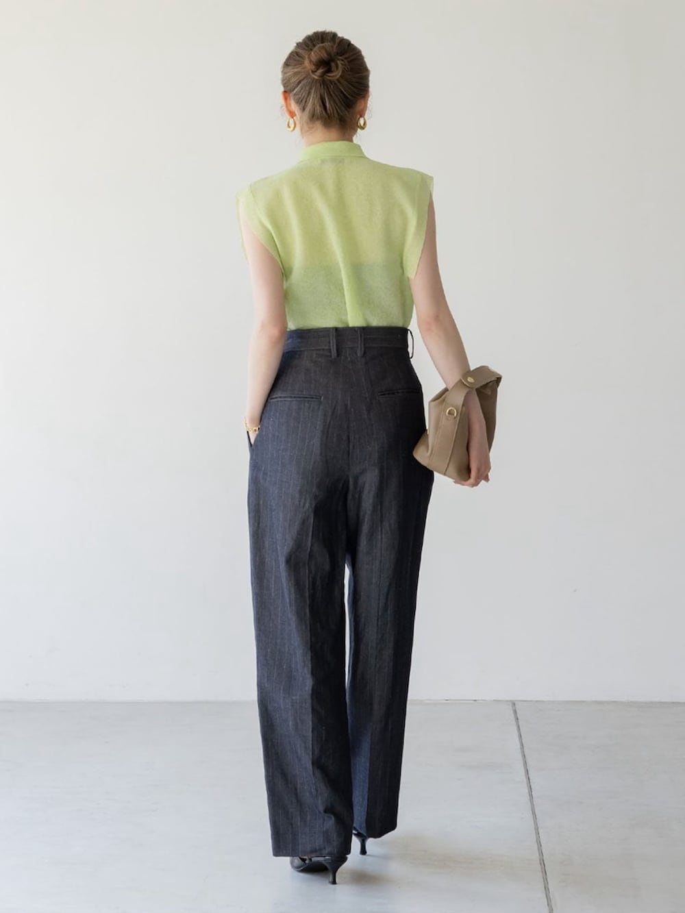 グリーン系のニット/セーター、ブルー系のスラックス、ホワイト系のショルダーバッグを着用したレディースの夏コーディネートの3枚目の写真