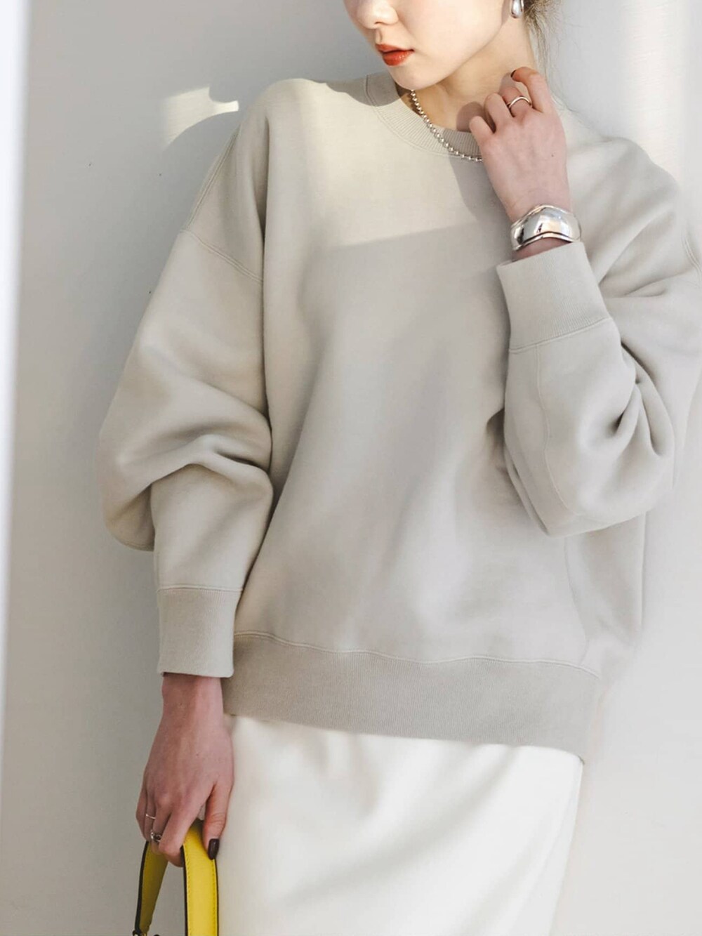 グレー系のスウェット、ホワイト系のスカート、シルバー系のパンプスを着用したレディースの冬コーディネートの3枚目の写真