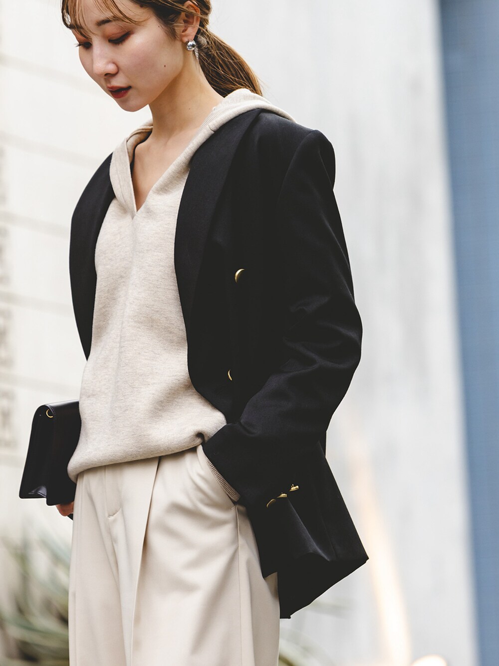 ブラック系のテーラードジャケット、ホワイト系のニット/セーター、ベージュ系のスラックスを着用したレディースの冬コーディネートの4枚目の写真