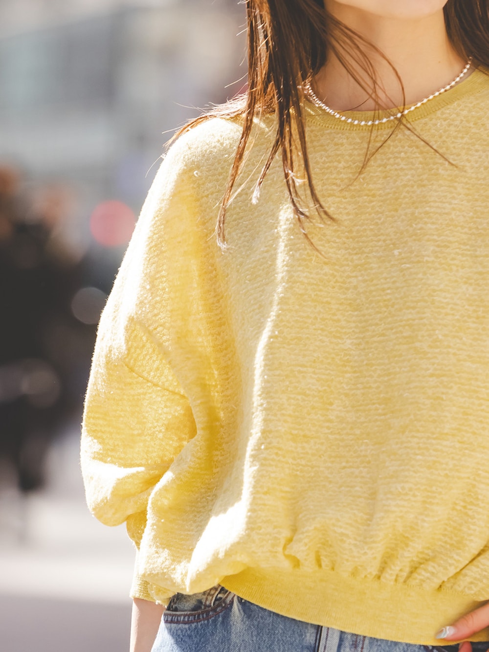 イエロー系のニット/セーター、ブルー系のデニムスカート、ベージュ系のサンダルを着用したレディースの春コーディネートの3枚目の写真