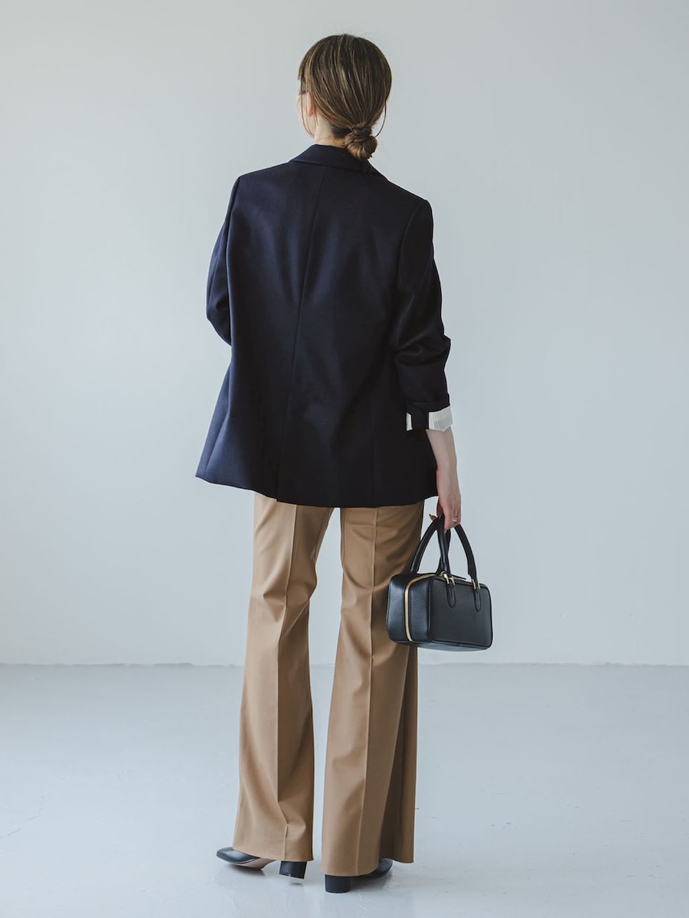 ブラック系のショルダーバッグ、イエロー系のスラックス、ホワイト系のキャミソールを着用したレディースの秋コーディネートの3枚目の写真