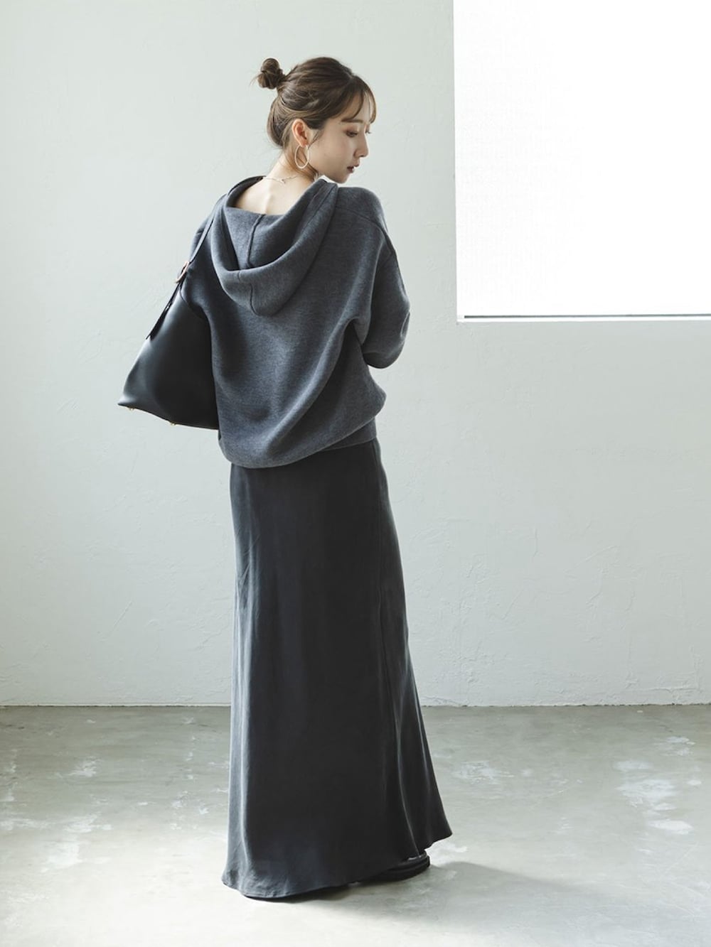 グレー系のニット/セーター、グレー系のスカート、ブラック系のショルダーバッグを着用したレディースの秋コーディネートの2枚目の写真