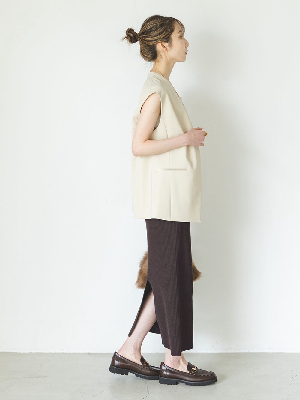 ベージュ系のベスト、ブラウン系のスカート、ブラック系のローファーを着用したレディースの夏コーディネートの2枚目の写真