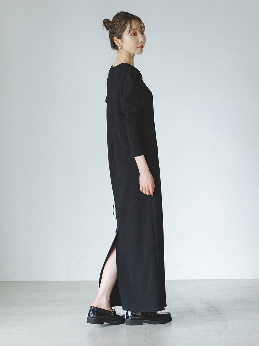 ブラック系のワンピース、ブラック系のバッグ、ブラック系のローファーを着用したレディースの秋コーディネートの2枚目の写真