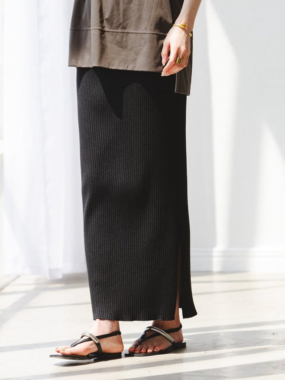 グリーン系のTシャツ/カットソー、ブラック系のスカート、ブラック系のサンダルを着用したレディースの夏コーディネートの3枚目の写真