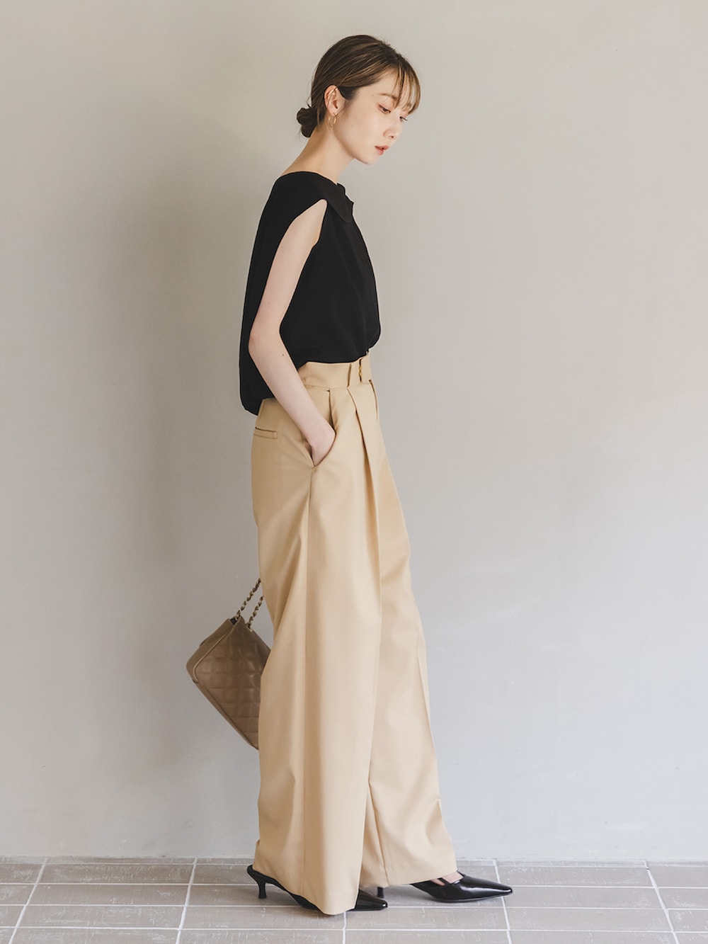 ブラック系のシャツ/ブラウス、ベージュ系のスラックス、ベージュ系のショルダーバッグを着用したレディースの夏コーディネートの2枚目の写真