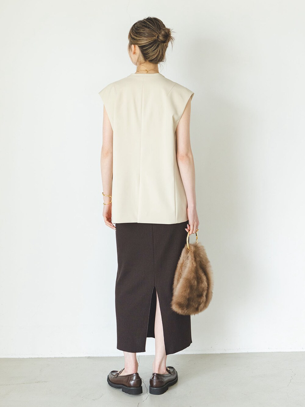 ベージュ系のベスト、ブラウン系のスカート、ブラック系のローファーを着用したレディースの夏コーディネートの3枚目の写真