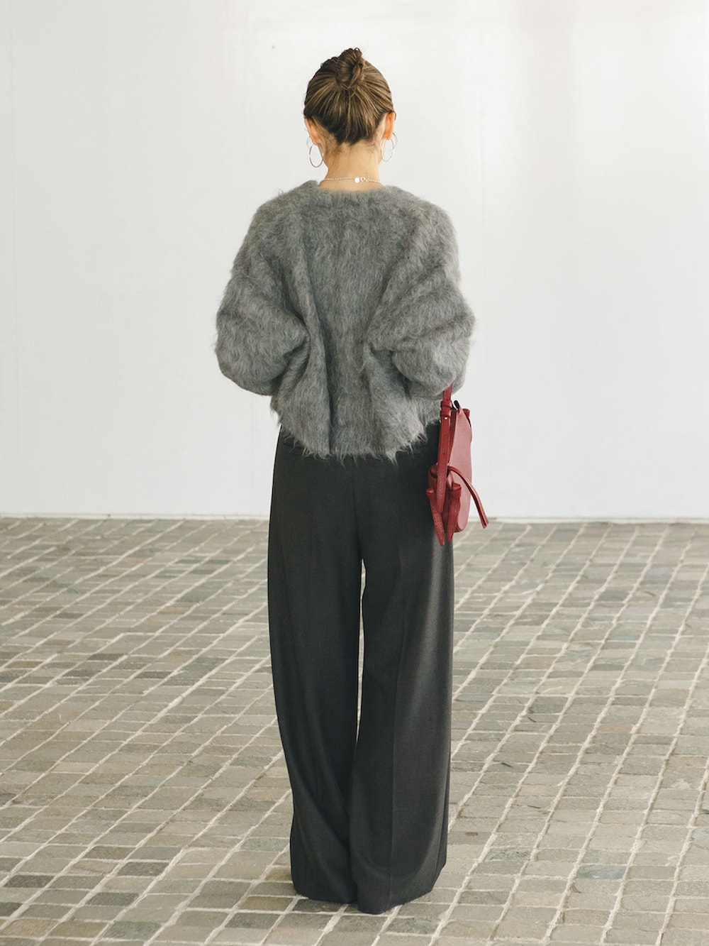 グレー系のカーディガン/ボレロ、グレー系のスラックス、レッド系のショルダーバッグを着用したレディースの秋コーディネートの2枚目の写真