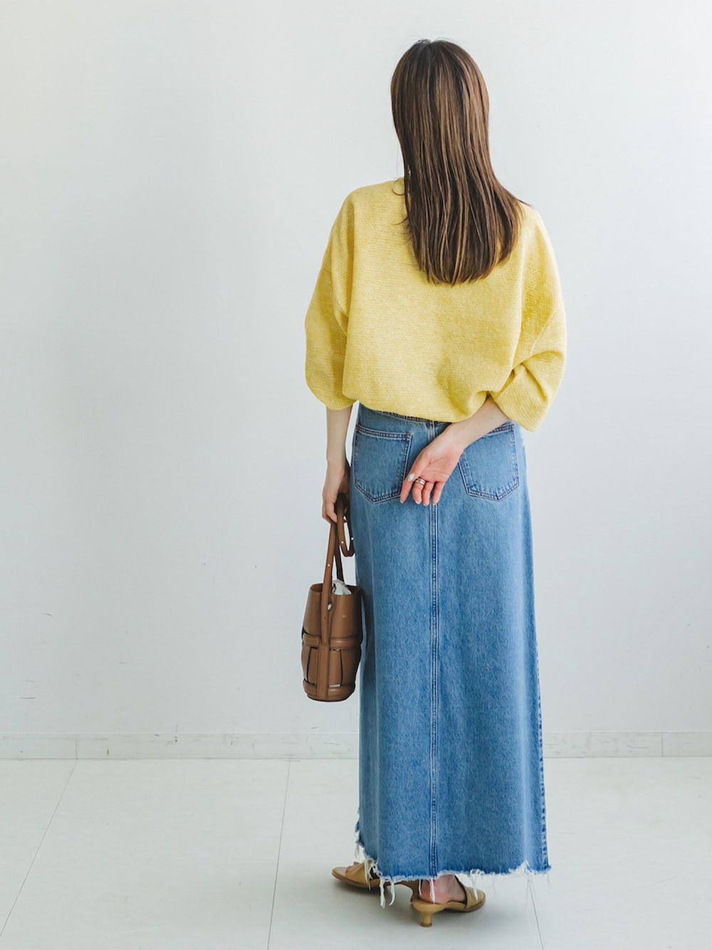 イエロー系のニット/セーター、ブルー系のデニムスカート、ベージュ系のサンダルを着用したレディースの春コーディネートの2枚目の写真