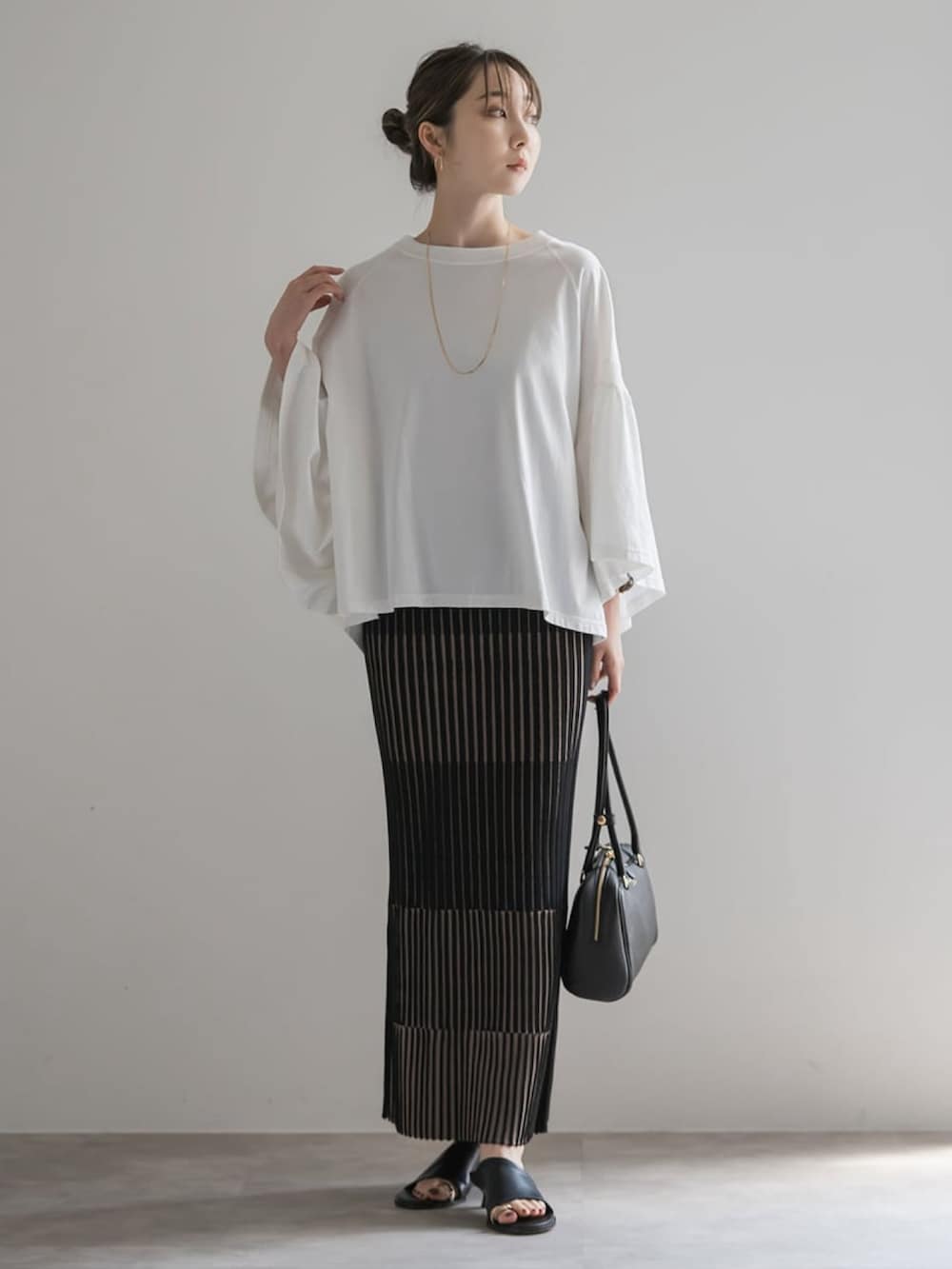 ホワイト系のTシャツ/カットソー、ブラック系のスカート、ブラウン系のボストンバッグを着用したレディースの夏コーディネートの2枚目の写真