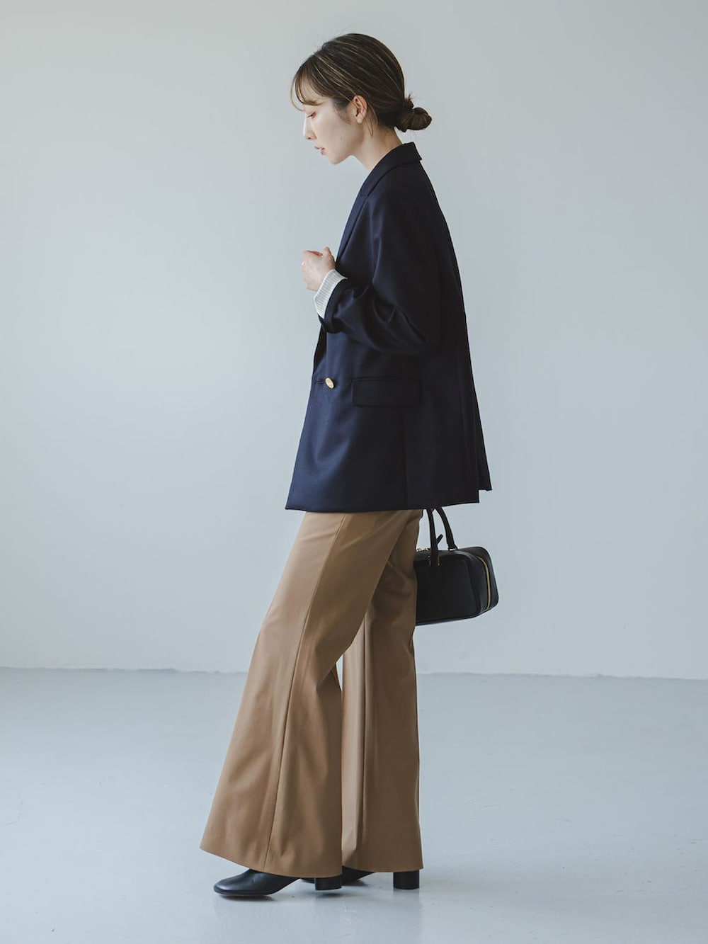 ブラック系のショルダーバッグ、イエロー系のスラックス、ホワイト系のキャミソールを着用したレディースの秋コーディネートの2枚目の写真