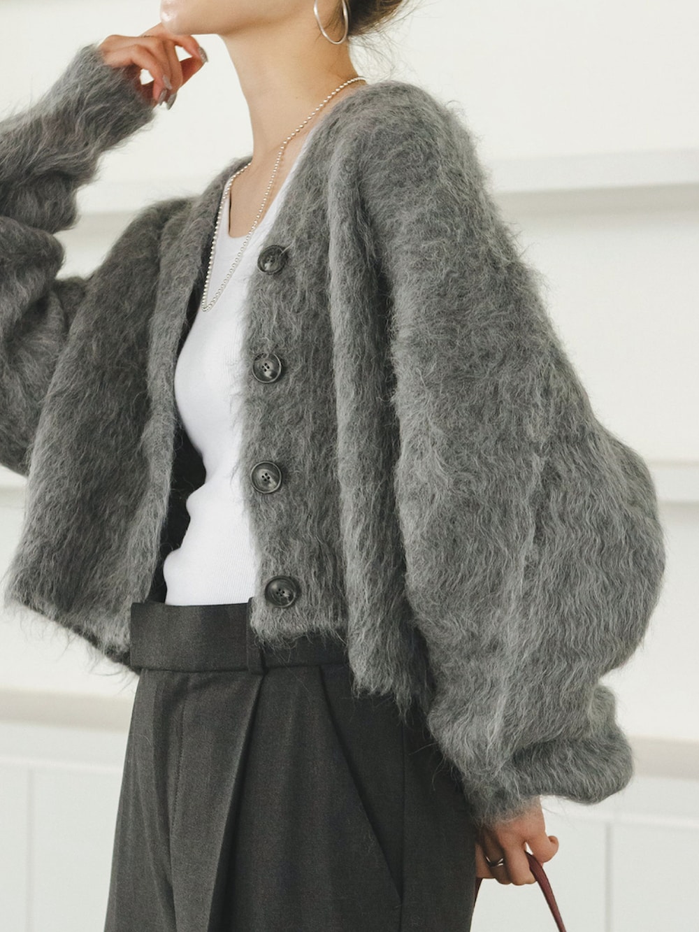 グレー系のカーディガン/ボレロ、グレー系のスラックス、レッド系のショルダーバッグを着用したレディースの秋コーディネートの3枚目の写真