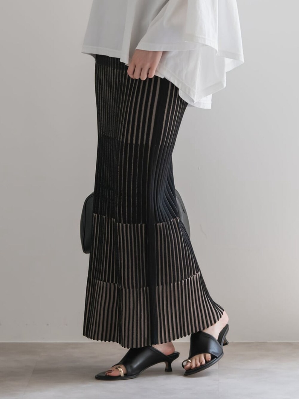 ホワイト系のTシャツ/カットソー、ブラック系のスカート、ブラウン系のボストンバッグを着用したレディースの夏コーディネートの4枚目の写真