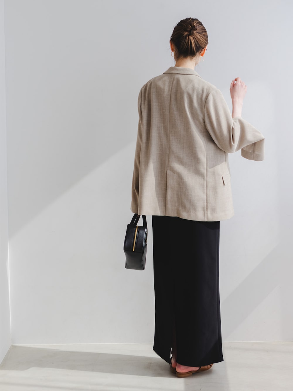 ベージュ系のテーラードジャケット、ブラック系のワンピース、ブラック系のショルダーバッグを着用したレディースの春コーディネートの2枚目の写真