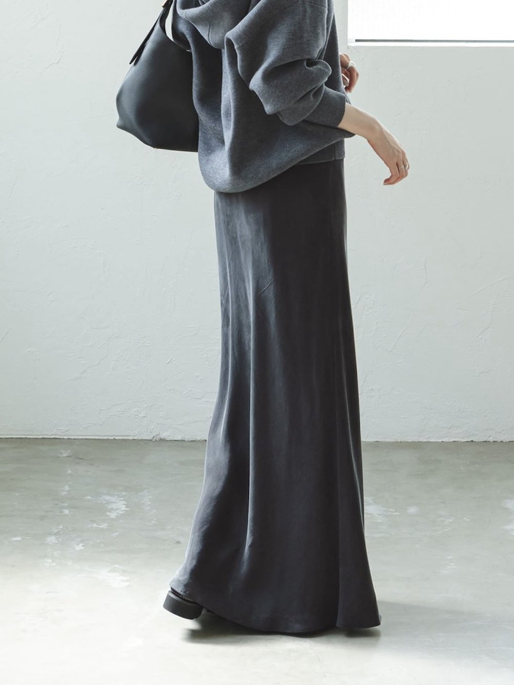 グレー系のニット/セーター、グレー系のスカート、ブラック系のショルダーバッグを着用したレディースの秋コーディネートの3枚目の写真