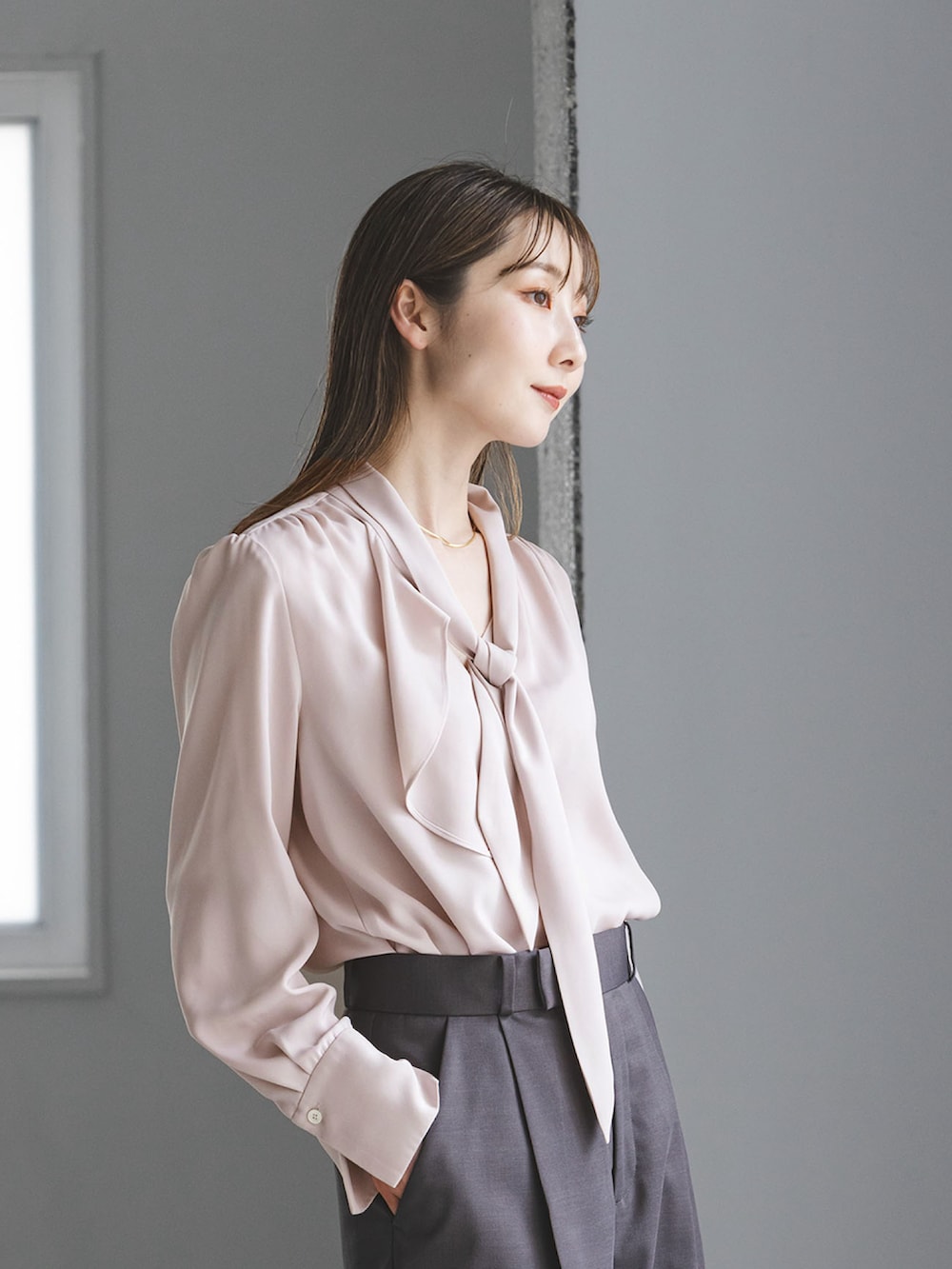 ピンク系のシャツ/ブラウス、グレー系のスラックス、ベージュ系のショルダーバッグを着用したレディースの秋コーディネートの3枚目の写真