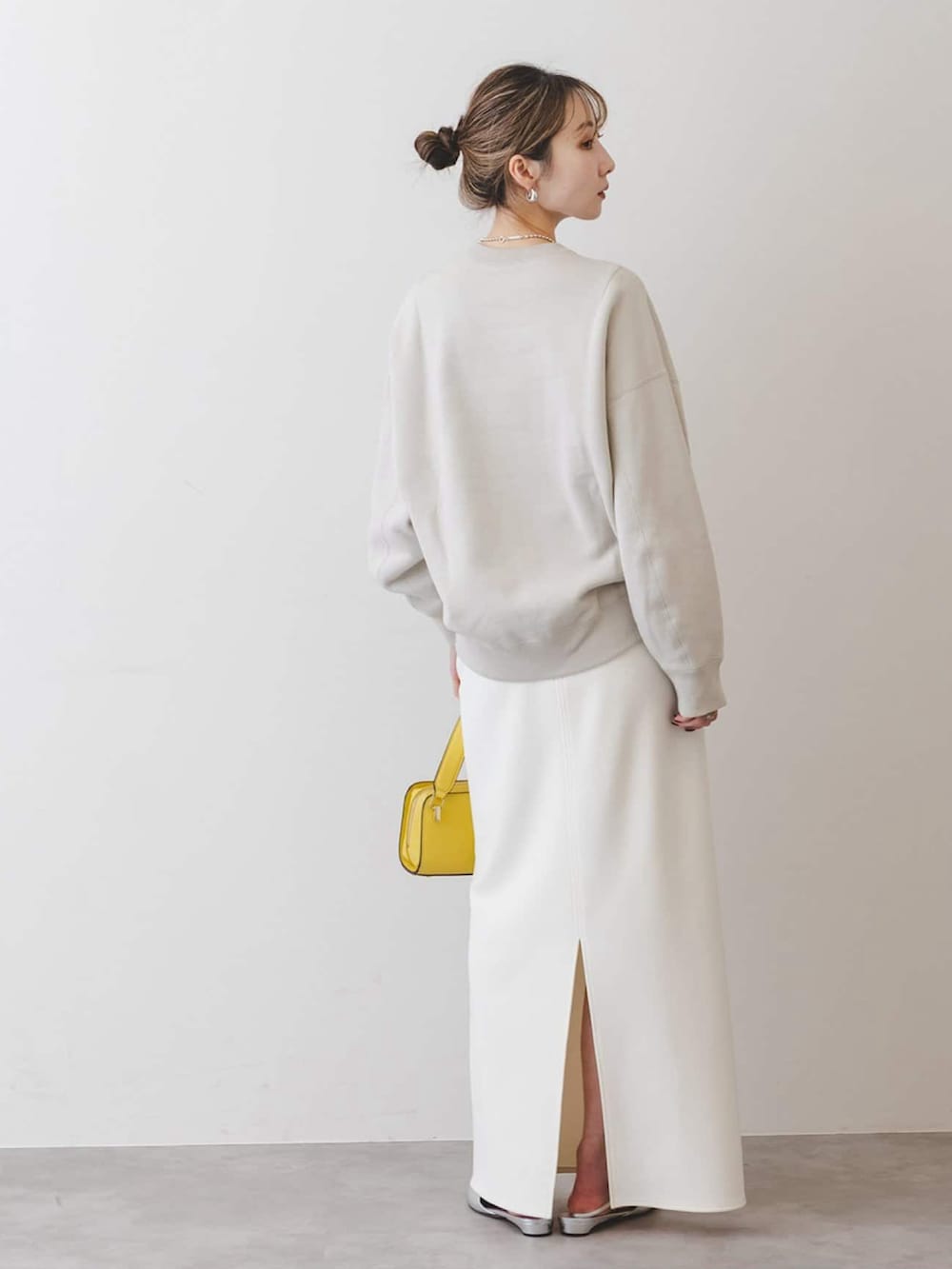 グレー系のスウェット、ホワイト系のスカート、シルバー系のパンプスを着用したレディースの冬コーディネートの2枚目の写真