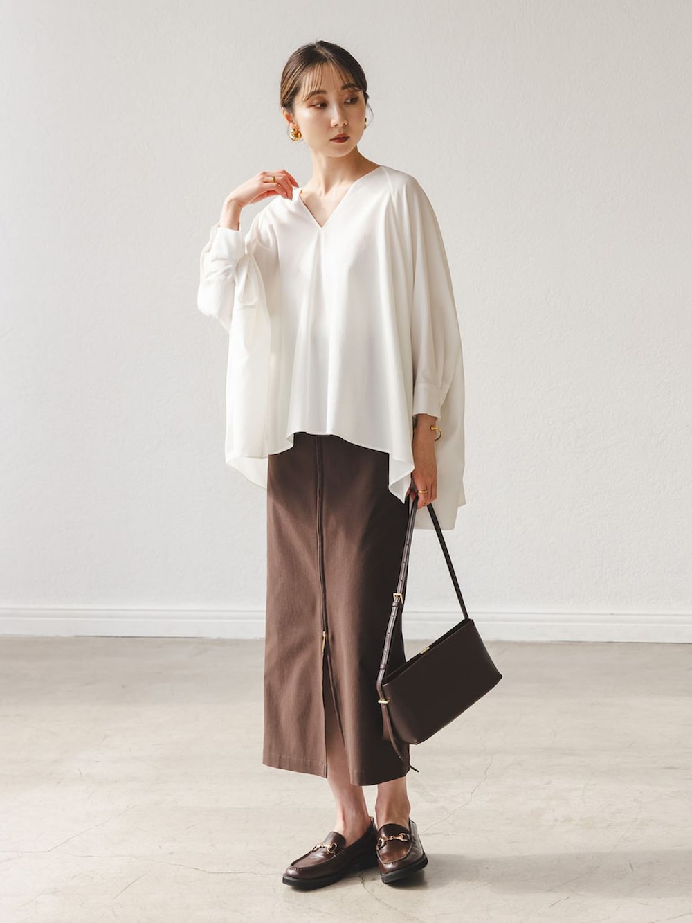 ホワイト系のシャツ/ブラウス、ブラウン系のスカート、ブラウン系のローファーを着用したレディースの秋コーディネートの2枚目の写真