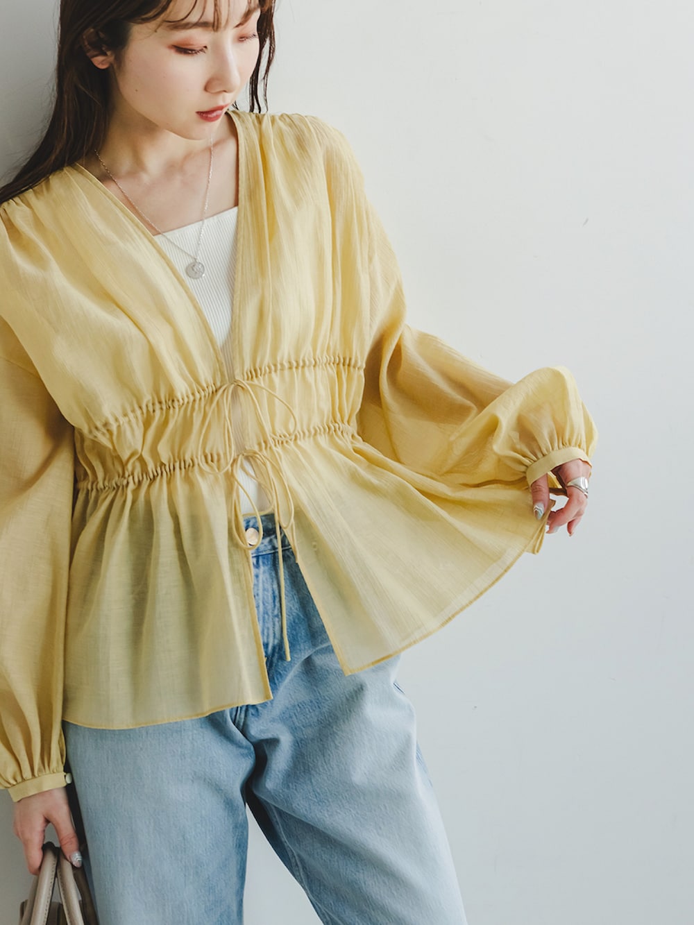 イエロー系のシャツ/ブラウス、ブルー系のデニムパンツ、ホワイト系のキャミソールを着用したレディースの春コーディネートの4枚目の写真