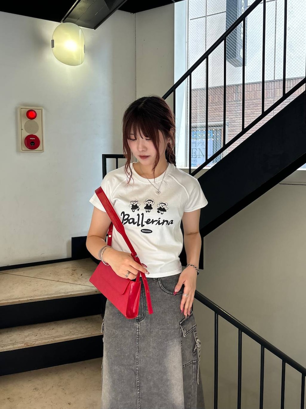 ブラック系のデニムスカート、レッド系のショルダーバッグ、ホワイト系のTシャツ/カットソーを着用したレディースの秋コーディネートの2枚目の写真