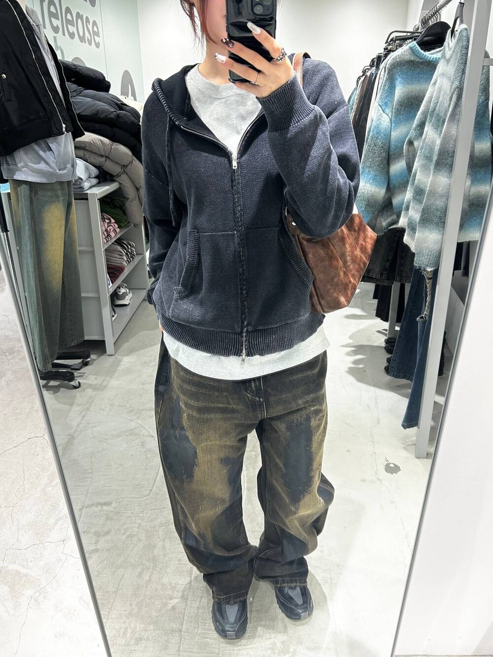 ブラック系のデニムパンツ、ブラウン系のハンドバッグ、ブラック系のパーカーを着用したレディースの冬コーディネートの2枚目の写真