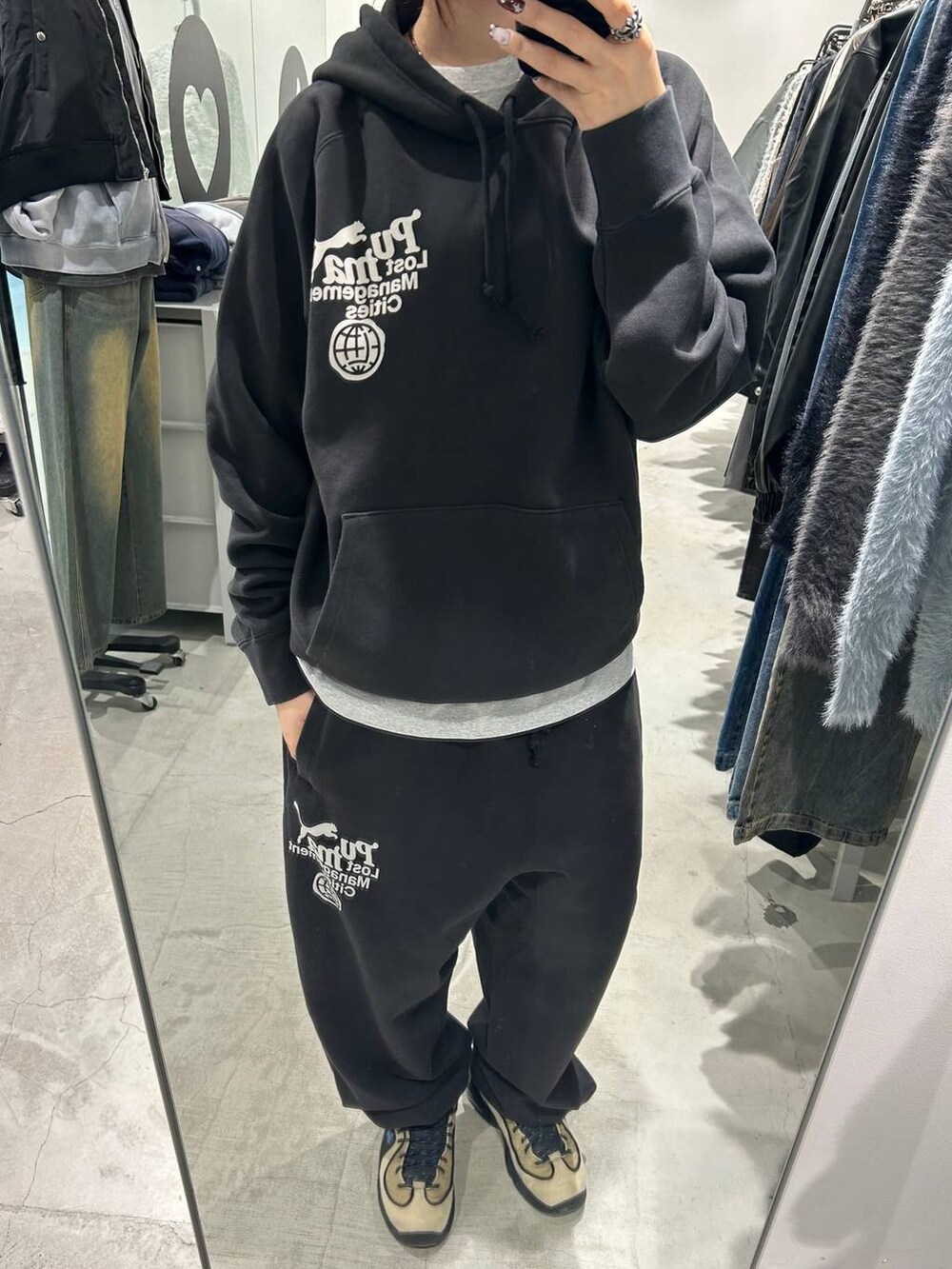 ブラック系のパーカー、ブラック系のスウェットパンツ、ホワイト系のキャップを着用したレディースの秋コーディネートの2枚目の写真