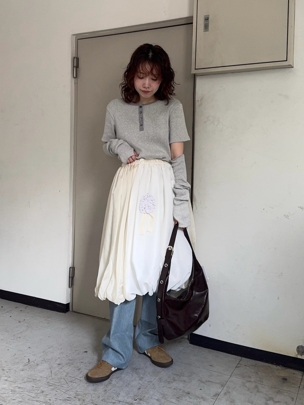 ブラウン系のハンドバッグ、ブルー系のデニムパンツ、ベージュ系のスニーカーを着用したレディースの秋コーディネートの2枚目の写真