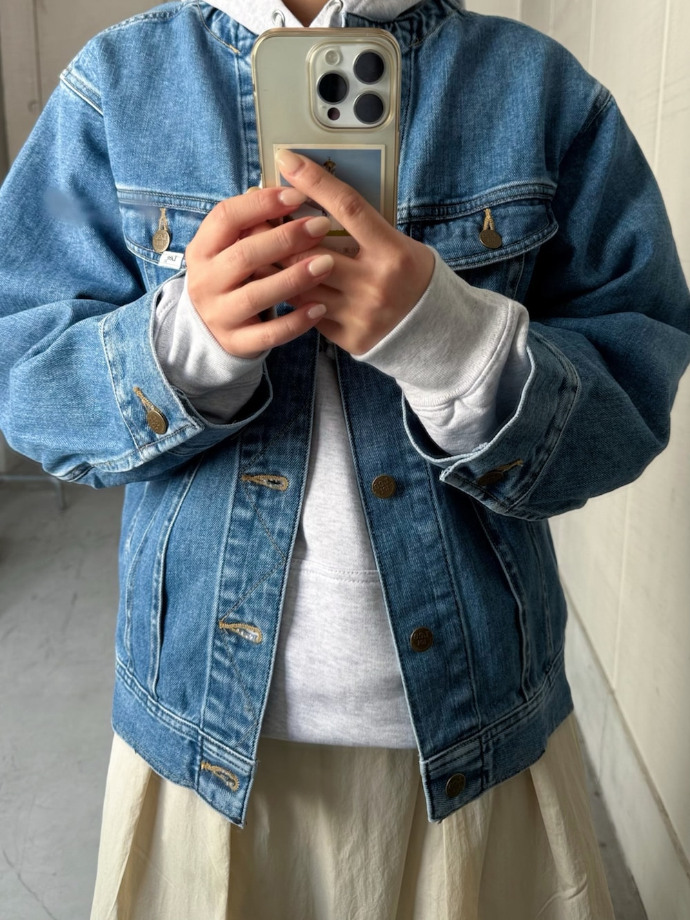 ブルー系のデニムジャケット、ベージュ系のショルダーバッグ、その他のパーカーを着用したレディースの冬コーディネートの3枚目の写真