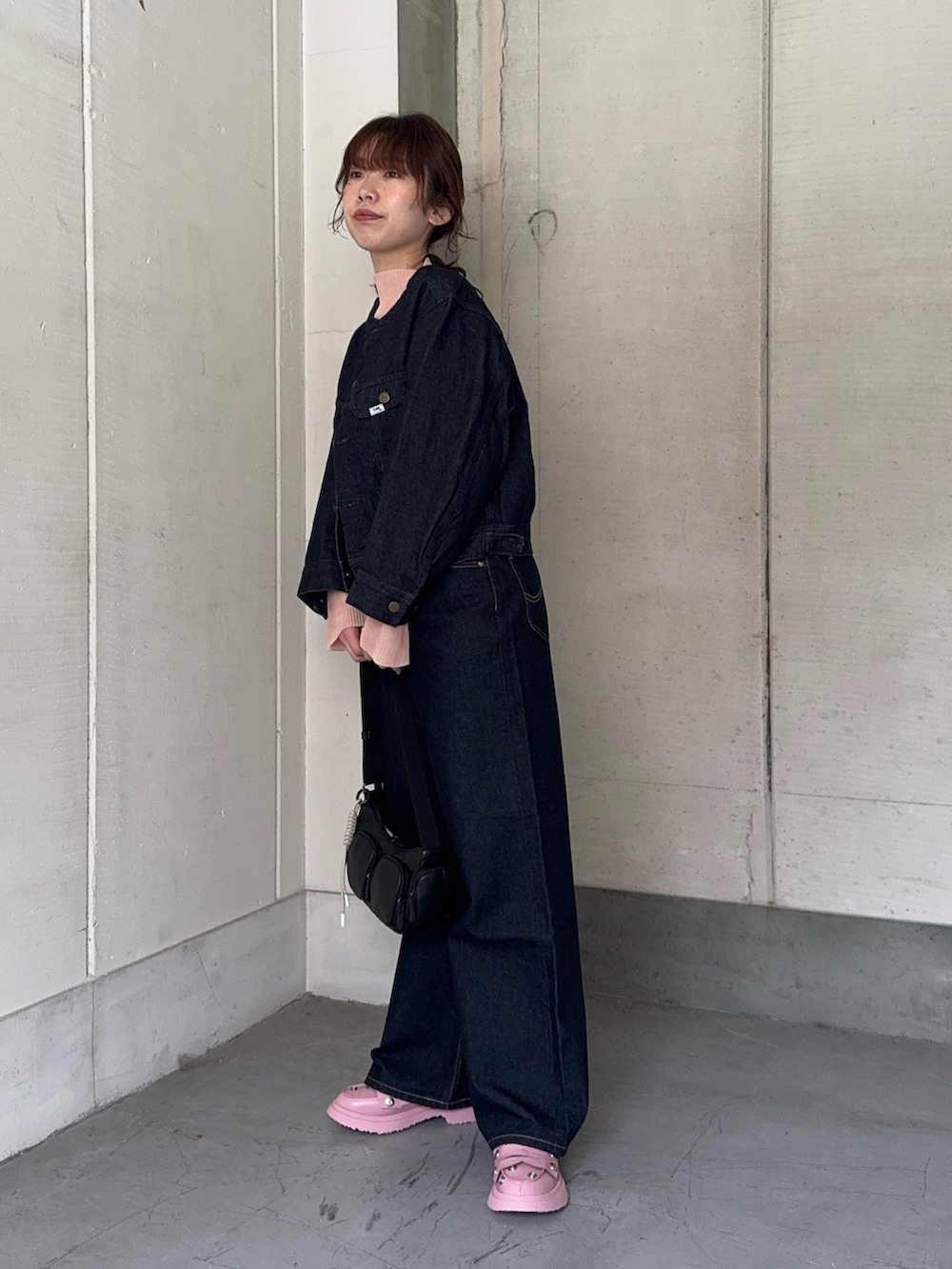 ブルー系のデニムジャケット、ブルー系のデニムパンツ、ブラック系のショルダーバッグを着用したレディースの冬コーディネートの2枚目の写真