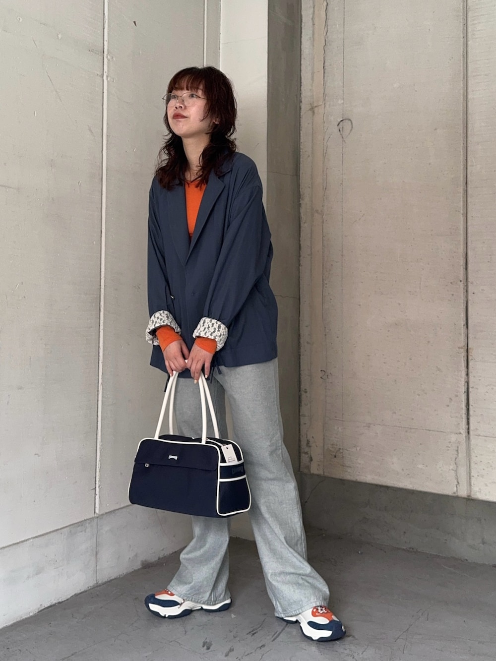 ブルー系のテーラードジャケット、オレンジ系のTシャツ/カットソー、ブルー系のデニムパンツを着用したレディースの冬コーディネートの2枚目の写真