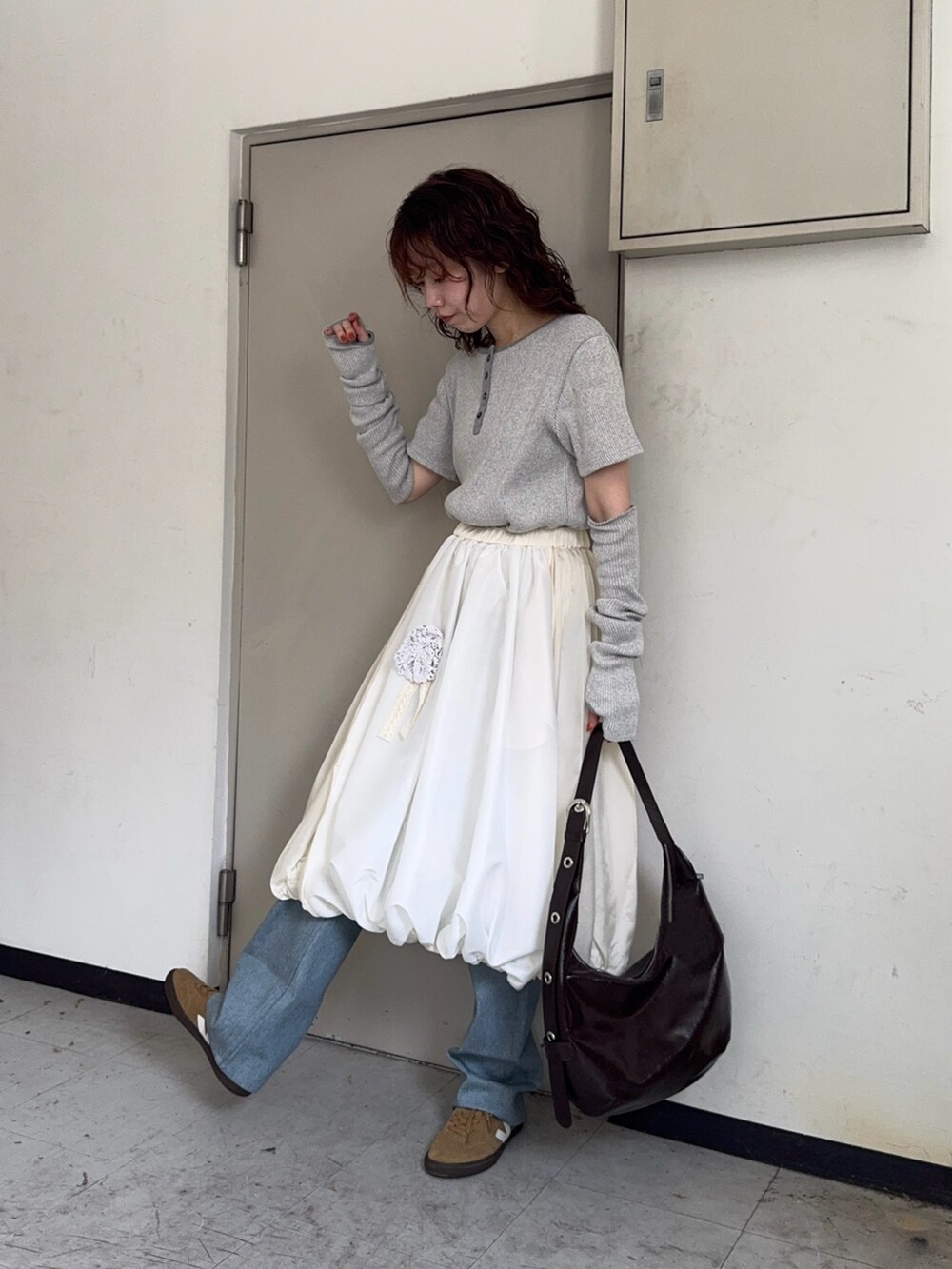 ブラウン系のハンドバッグ、ブルー系のデニムパンツ、ベージュ系のスニーカーを着用したレディースの秋コーディネートの3枚目の写真