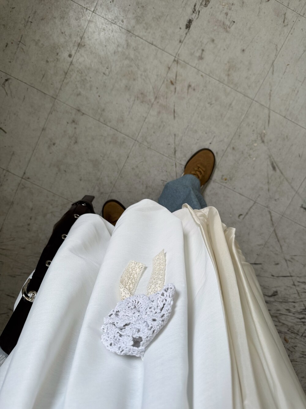 ブラウン系のハンドバッグ、ブルー系のデニムパンツ、ベージュ系のスニーカーを着用したレディースの秋コーディネートの4枚目の写真