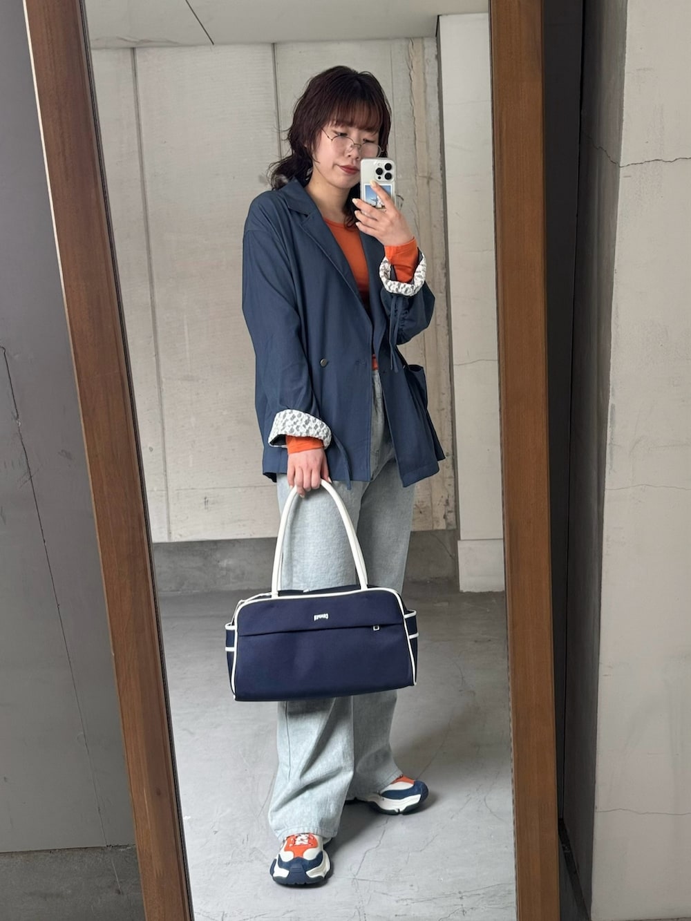 ブルー系のテーラードジャケット、オレンジ系のTシャツ/カットソー、ブルー系のデニムパンツを着用したレディースの冬コーディネートの3枚目の写真