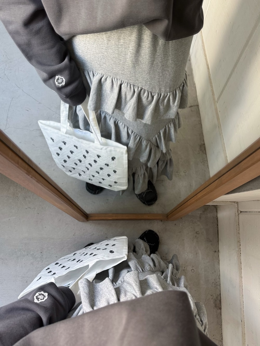 グレー系のスウェット、グレー系のスカート、ホワイト系のトートバッグを着用したレディースの冬コーディネートの3枚目の写真