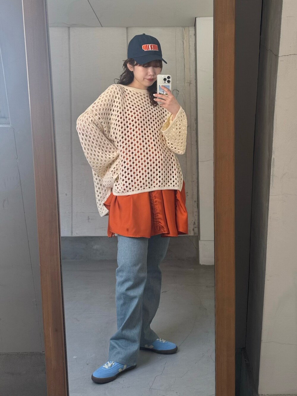 ホワイト系のニット/セーター、オレンジ系のワンピース、ブルー系のデニムパンツを着用したレディースの春コーディネートの6枚目の写真