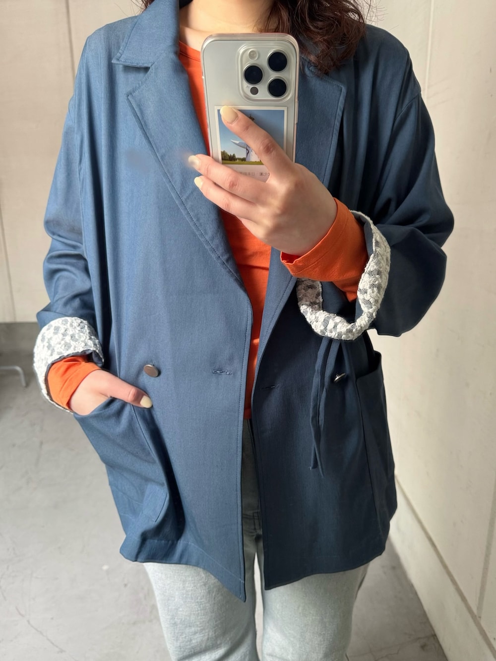 ブルー系のテーラードジャケット、オレンジ系のTシャツ/カットソー、ブルー系のデニムパンツを着用したレディースの冬コーディネートの4枚目の写真