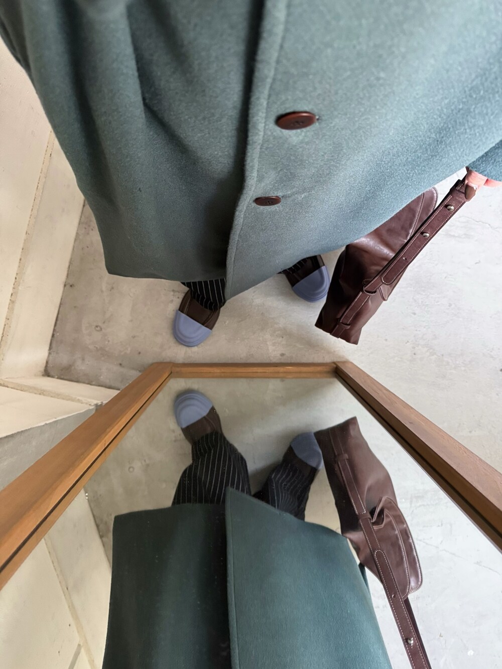 グリーン系のステンカラーコート、ブラック系のその他パンツ、ブラウン系のショルダーバッグを着用したレディースの秋コーディネートの3枚目の写真