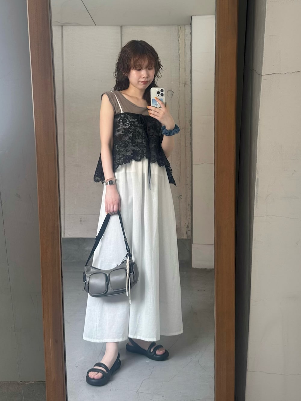 ブラック系のスカート、ホワイト系のワンピース、ブラウン系のショルダーバッグを着用したレディースの夏コーディネートの2枚目の写真