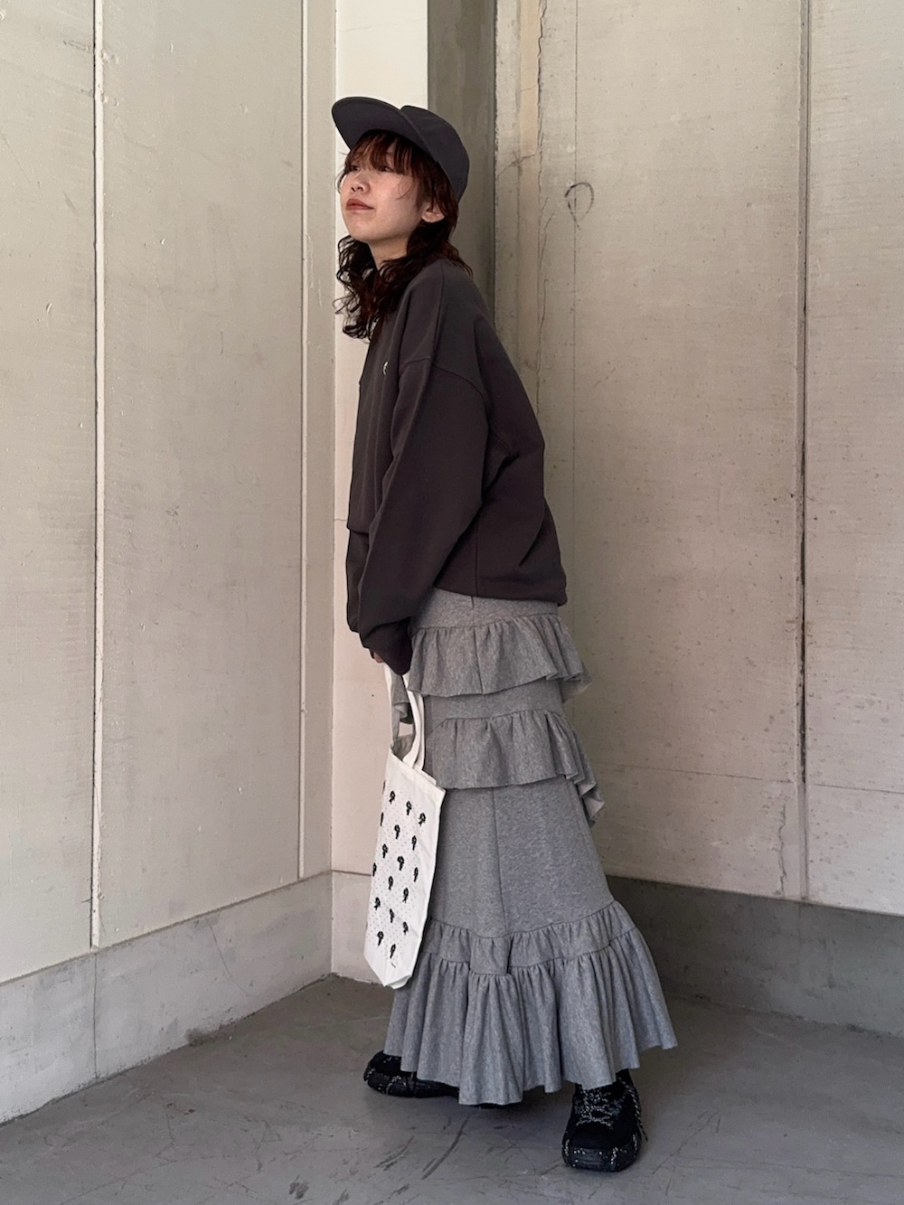 グレー系のスウェット、グレー系のスカート、ホワイト系のトートバッグを着用したレディースの冬コーディネートの2枚目の写真