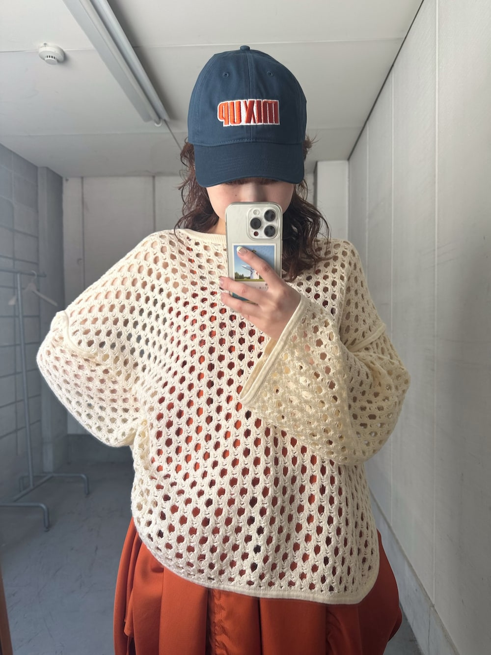 ホワイト系のニット/セーター、オレンジ系のワンピース、ブルー系のデニムパンツを着用したレディースの春コーディネートの5枚目の写真