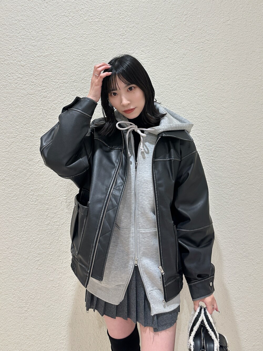 ブラック系のブルゾン、グレー系のパーカー、ブラック系のハンドバッグを着用したレディースの秋コーディネートの4枚目の写真