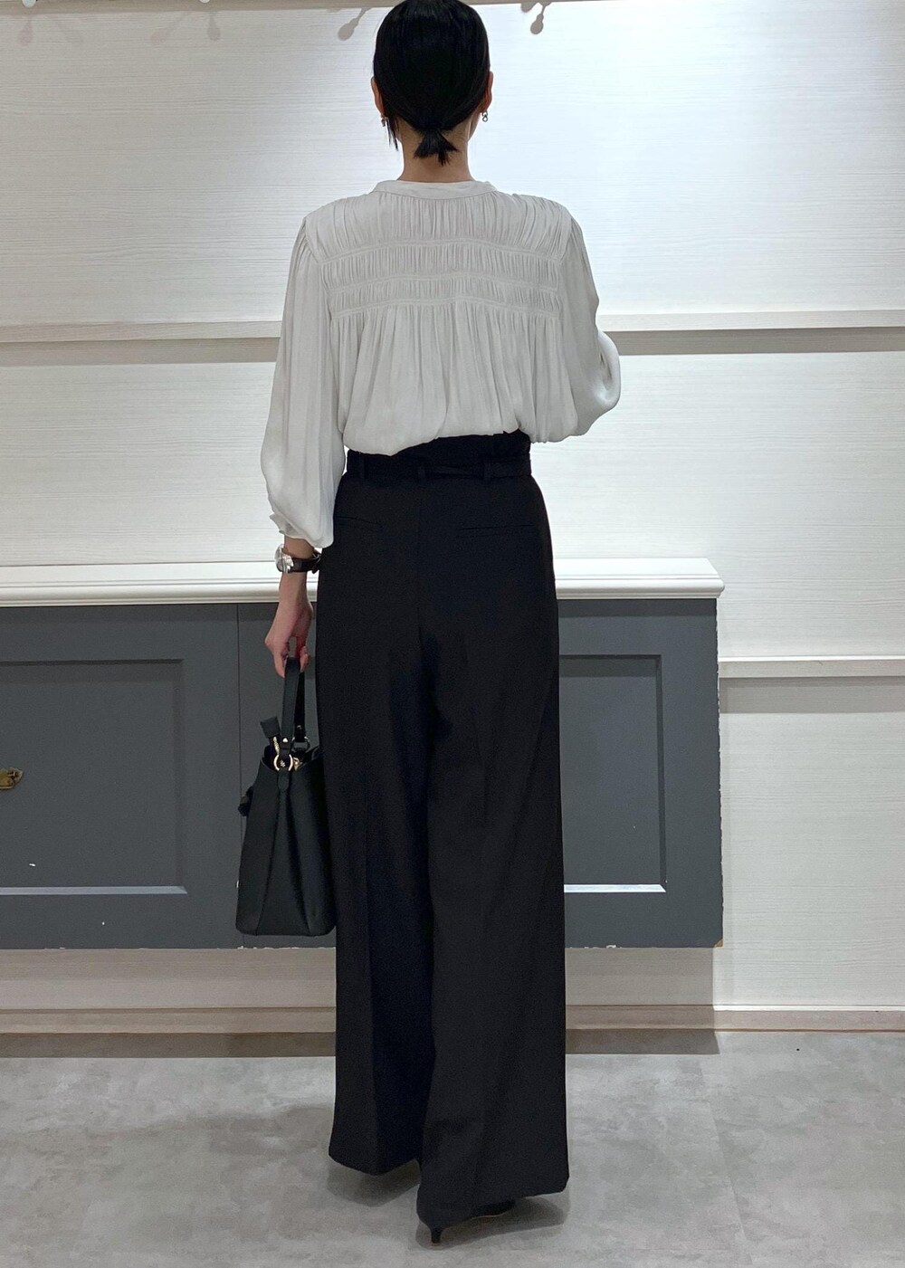 ブラック系のパンプス、ブラック系のショルダーバッグ、ブラック系のスラックスを着用したレディースの夏コーディネートの2枚目の写真