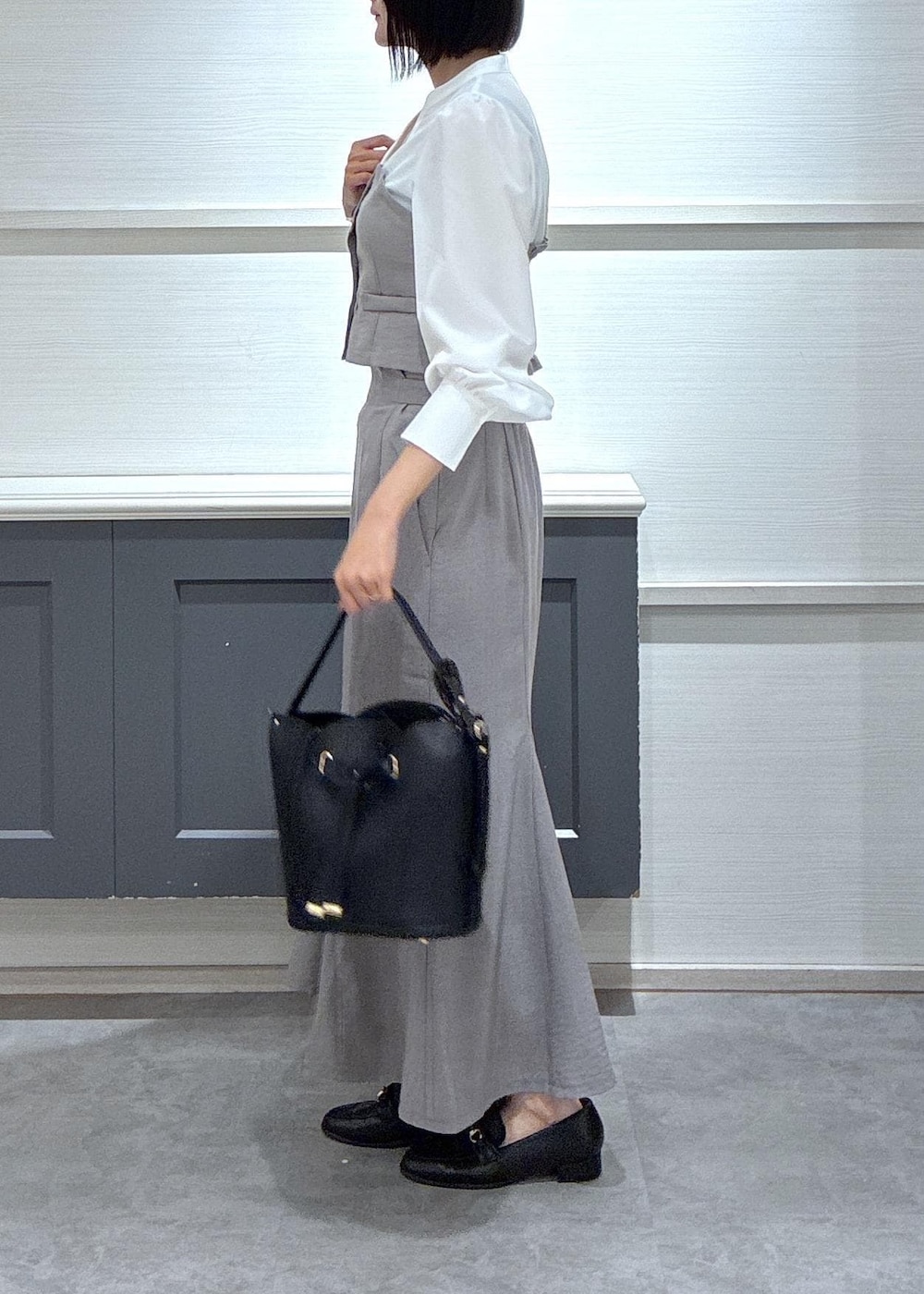 ブラック系のショルダーバッグ、ブラック系のローファー、グレー系のスカートを着用したレディースの春コーディネートの4枚目の写真