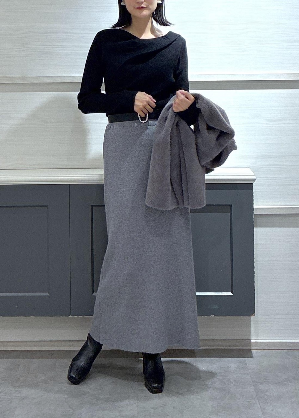 ブラック系のショルダーバッグ、ブラック系のブーツ、グレー系のスカートを着用したレディースの秋コーディネートの2枚目の写真