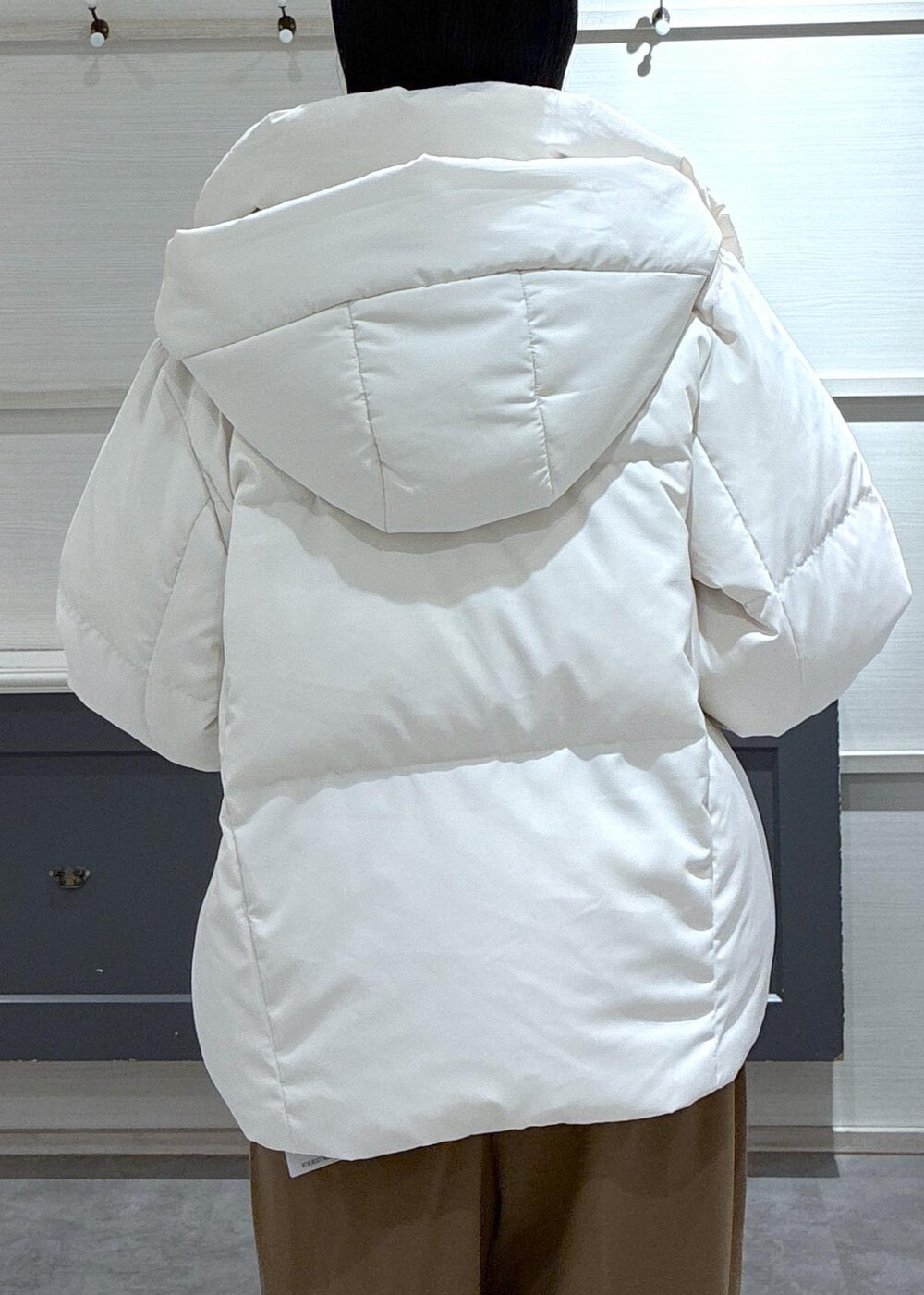 ブラック系のタンクトップ、ホワイト系のダウンジャケット/コート、ブラック系のブーツを着用したレディースの秋コーディネートの7枚目の写真