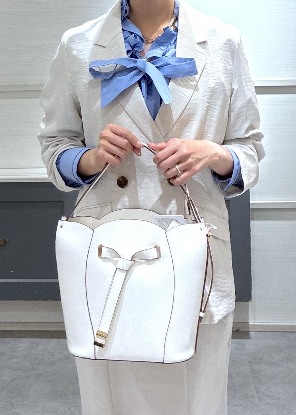 ホワイト系のショルダーバッグ、ベージュ系のパンプス、ブルー系のシャツ/ブラウスを着用したレディースの春コーディネートの3枚目の写真