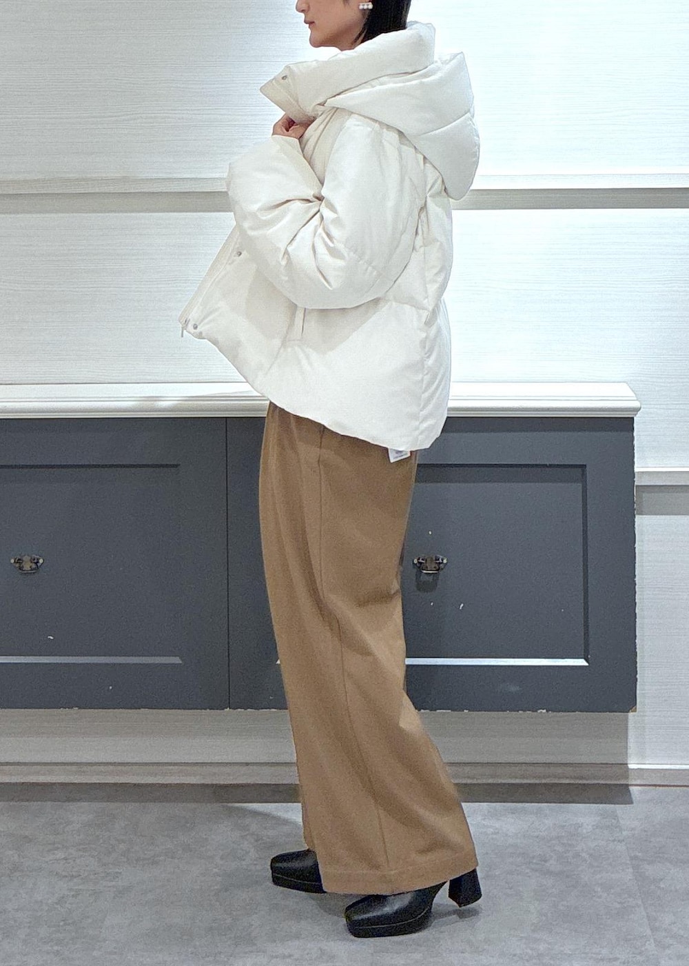 ブラック系のタンクトップ、ホワイト系のダウンジャケット/コート、ブラック系のブーツを着用したレディースの秋コーディネートの3枚目の写真